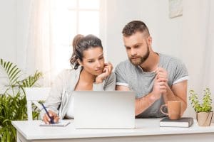 A couple researches on a computer, deciding whether to renovate or relocate